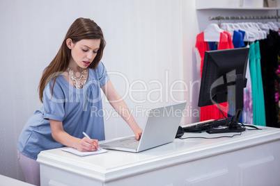 Shop worker using laptop by the till