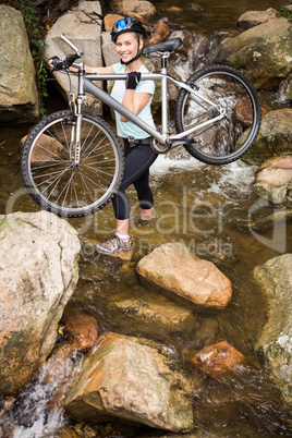 Smiling fit woman lifting her bike