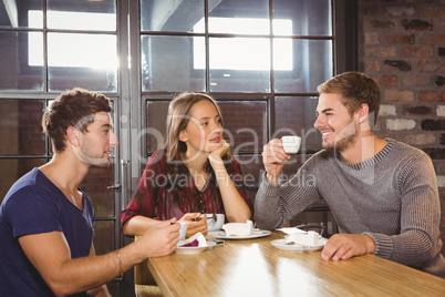 Smiling friends talking and enjoying coffee and cake