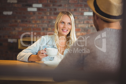 Smiling blonde drinking coffee with friend