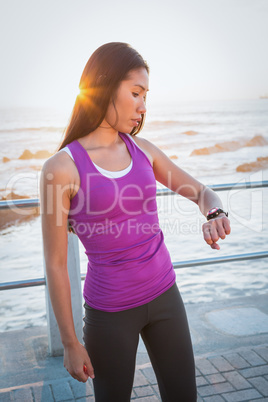 Fit woman checking smart watch at promenade