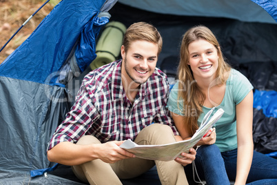 Young pretty hiker couple sitting in a tent looking at camera