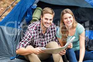 Young pretty hiker couple sitting in a tent looking at camera