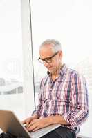 Smiling casual businessman using laptop