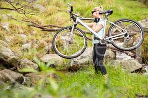 Side view of a fit woman lifting her bike