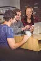 Smiling friends looking at smartphone