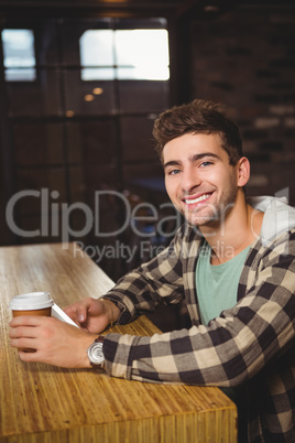 Smiling hipster holding smartphone and take-away cup