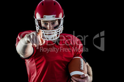 Portrait of american football player holding football and pointi