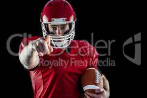 Portrait of american football player holding football and pointi