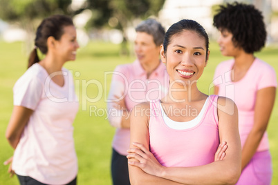 Smiling woman wearing pink for breast cancer in front of friends