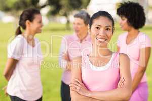 Smiling woman wearing pink for breast cancer in front of friends