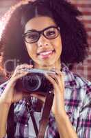 Attractive smiling hipster holding camera
