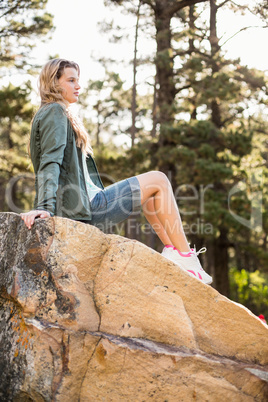 Young jogger sitting on rock and looking away