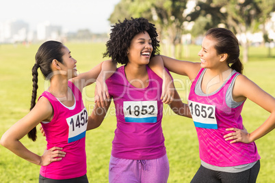 Three laughing runners supporting breast cancer marathon