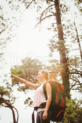 Smiling blonde hiker pointing far away