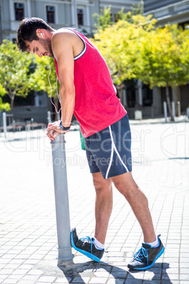 Handsome athlete doing leg stretching on a stake
