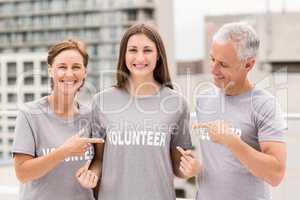 Smiling volunteers pointing on shirt