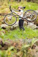 Side view of a fit woman lifting her bike