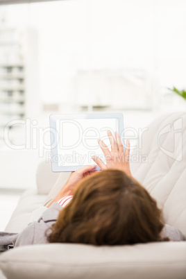 Casual businesswoman relaxing on couch with tablet