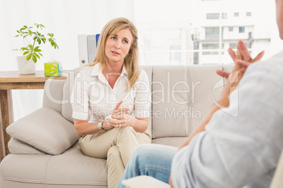 Unhappy woman sitting on couch and talking to therapist