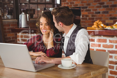 Cute couple on a date watching photos on a laptop