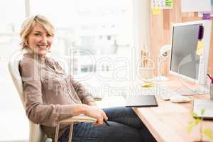 Smiling casual designer sitting at desk