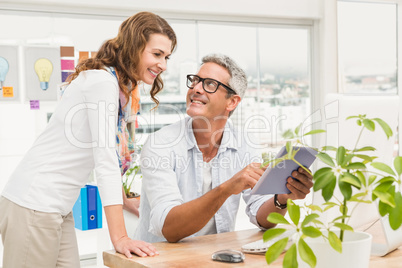 Two smiling casual designers working with tablet