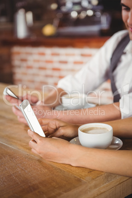 Cute couple sitting in cafe looking at smartphone