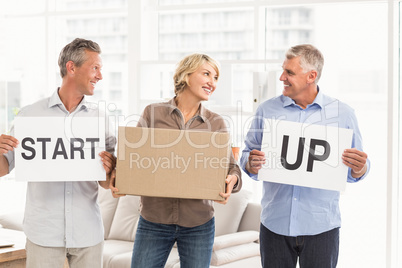 Smiling casual business people holding start up sign