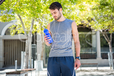 Handsome runner holding a water bottle