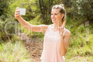 Pretty blonde showing peace sign and taking selfies