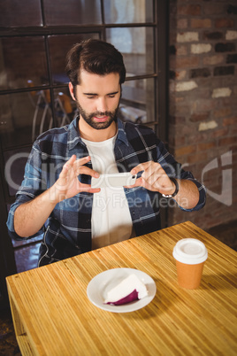 Handsome man taking a picture of his cake and coffee