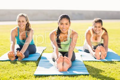 Smiling sporty women stretching on exercise mat