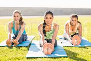Smiling sporty women stretching on exercise mat