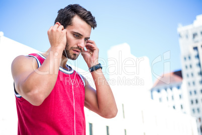 Serious handsome athlete putting on his earphones