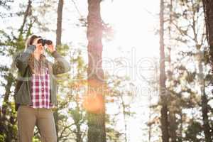 Blonde hiker looking through binoculars