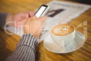 Man using smartphone and drinking cappuccino