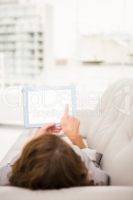 Casual businesswoman relaxing on couch with tablet