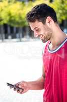 Smiling handsome athlete sending a text