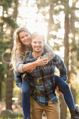 Smiling handsome man giving piggy back to his girlfriend