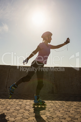 Focused sporty blonde skating against blue sky