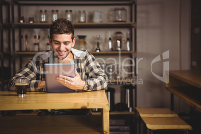 Smiling hipster having coffee and using tablet computer