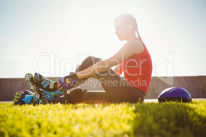 Smiling sporty blonde skater sitting in grass
