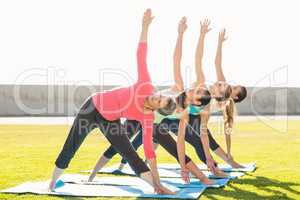 Sporty women doing triangle pose in yoga class