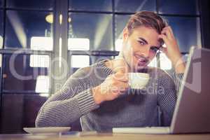 Handsome man smiling and drinking coffee