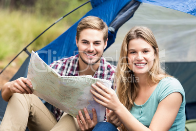 Young pretty hiker couple sitting in a tent looking at camera
