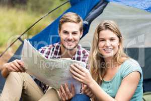 Young pretty hiker couple sitting in a tent looking at camera