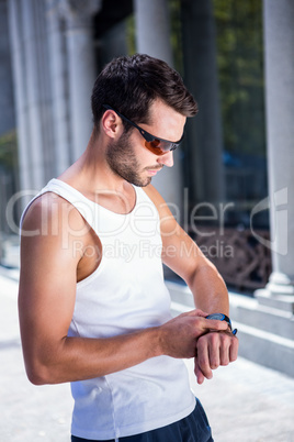 Handsome athlete with sunglasses setting heart rate watch