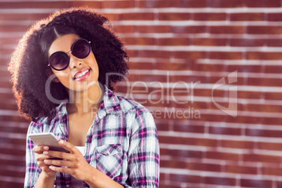 Attractive smiling hipster holding smartphone