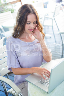 Woman using laptop on cafe terrace
